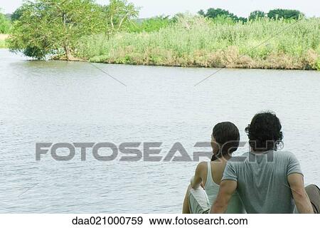 Couple sitting by lake, rear view View Large Photo Image Stock Photo - Couple sitting by lake, rear view. Fotosearch