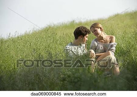 Stock Photography - Couple sitting in grass. Fotosearch