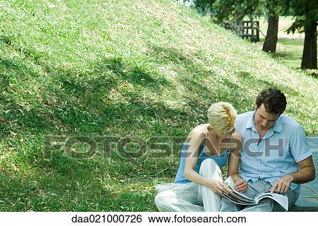 Couple sitting outdoors, looking at catalog together View Large Photo Image Stock Photograph - Couple sitting outdoors, looking at catalog together. Fotosearch