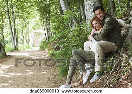 Couple sitting together beside wooded path, portrait View Large Photo Image Stock Image - Couple sitting together beside wooded path, portrait. Fotosearch