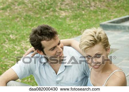 Stock Image - Couple sitting together outdoors, portrait. Fotosearch