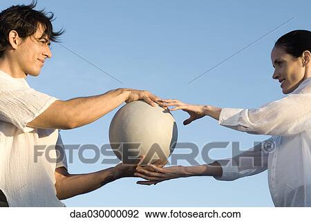 Couple standing face to face, man passing ball to woman, low angle view View Large Photo Image Stock Image - Couple standing face to face, man passing ball to woman, low angle view. Fotosearch