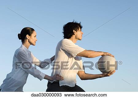 Couple together outdoors, man holding ball, woman holding man's hips View Large Photo Image Stock Image - Couple together outdoors, man holding ball, woman holding man's hips. Fotosearch