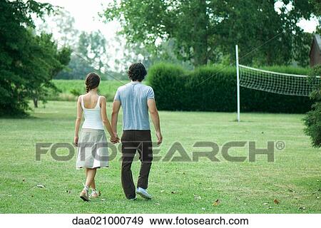 Stock Photo - Couple walking across grass toward badminton net. Fotosearch