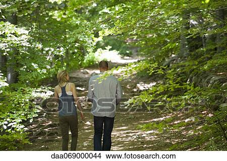 Picture - Couple walking in woods, rear view. Fotosearch