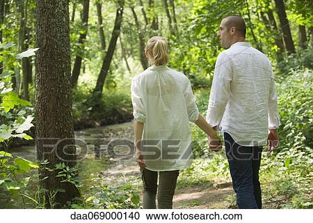 Couple walking in woods, rear view View Large Photo Image Stock Image - Couple walking in woods, rear view. Fotosearch
