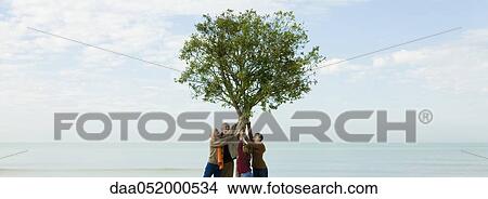 Picture - Ecology concept, group of people supporting tree together. Fotosearch