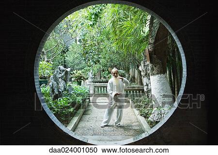 Stock Image - Elderly man wearing traditional Chinese clothing doing Tai Chi. Fotosearch