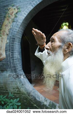 Stock Image - Elderly man wearing traditional Chinese clothing, looking up, side view. Fotosearch