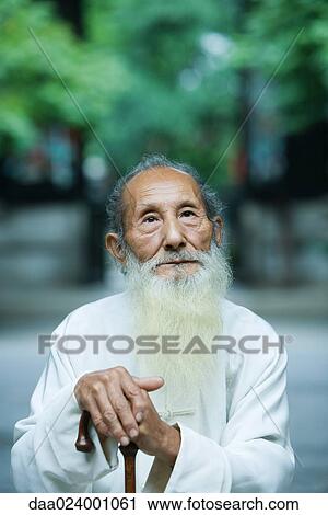 Stock Image - Elderly man wearing traditional Chinese clothing, holding cane. Fotosearch