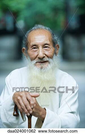 Stock Image - Elderly man wearing traditional Chinese clothing, holding cane. Fotosearch
