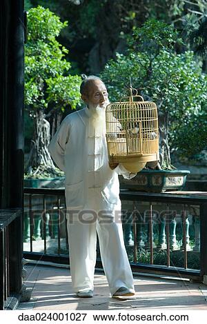 Stock Photo - Elderly man wearing traditional Chinese clothing, carrying bird cage. Fotosearch