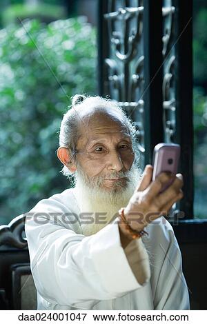 Stock Photo - Elderly man wearing traditional Chinese clothing using camera phone. Fotosearch