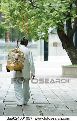 Stock Photo - Elderly man wearing traditional Chinese clothing carrying bird cage over shoulder, rear view. Fotosearch