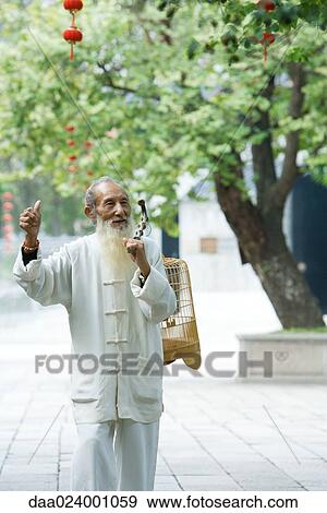 Elderly man wearing traditional Chinese clothing carrying bird cage over shoulder, holding up thumb View Large Photo Image Stock Photo - Elderly man wearing traditional Chinese clothing carrying bird cage over shoulder, holding up thumb. Fotosearch