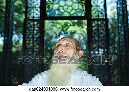 Stock Photograph - Elderly man with long beard, looking up, low angle view, portrait. Fotosearch