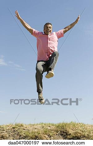 Excited man jumping into the air with arms raised View Large Photo Image Stock Photo - Excited man jumping into the air with arms raised. Fotosearch
