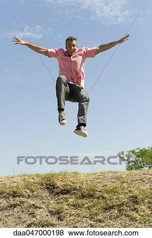 Stock Photo - Excited man jumping into the air with arms raised. Fotosearch