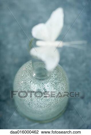 Stock Image - Fake butterfly balancing on bottle. Fotosearch