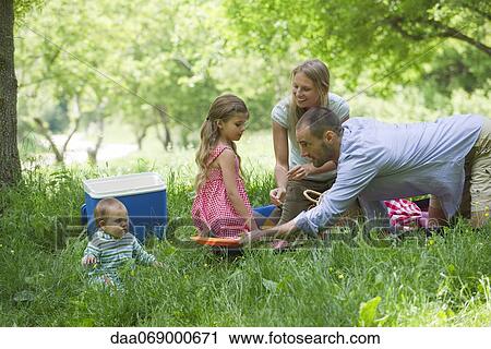 Stock Image - Family having picnic in meadow. Fotosearch