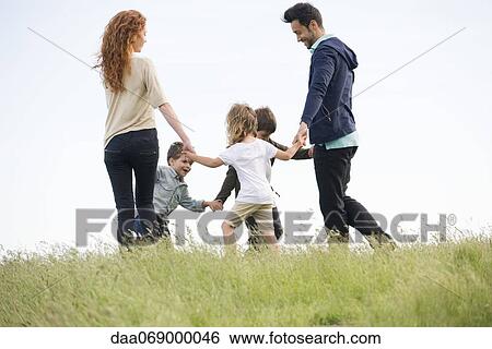 Stock Photograph - Family playing ring-around-the-rosy in meadow. Fotosearch