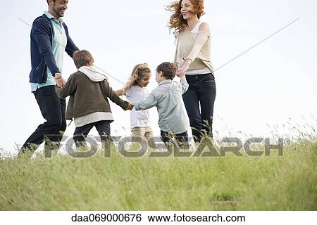 Family playing ring-around-the-rosy in meadow View Large Photo Image Stock Photograph - Family playing ring-around-the-rosy in meadow. Fotosearch