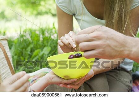 Family sharing bowl of cherries outdoors, cropped View Large Photo Image Stock Image - Family sharing bowl of cherries outdoors, cropped. Fotosearch
