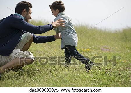 Stock Photography - Father and son playing together outdoors. Fotosearch