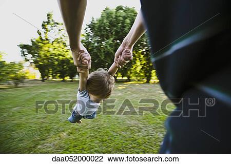 Father spinning little boy in park, cropped View Large Photo Image Stock Image - Father spinning little boy in park, cropped. Fotosearch
