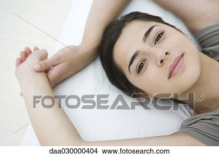 Female lying on pillow, arms raised, smiling at camera View Large Photo Image Picture - Female lying on pillow, arms raised, smiling at camera. Fotosearch