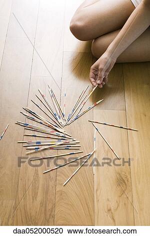 Stock Image - Female playing with pick up sticks on floor. Fotosearch