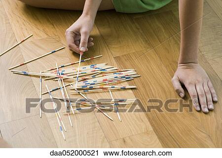 Stock Image - Female playing with pick up sticks on floor. Fotosearch
