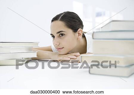 Female student between two stacks of books, head resting on arms, looking away View Large Photo Image Stock Image - Female student between two stacks of books, head resting on arms, looking away. Fotosearch