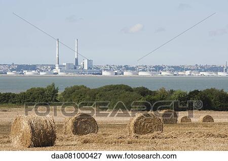 Field with bales of hay in foreground, power station in background View Large Photo Image Stock Photo - Field with bales of hay in foreground, power station in background. Fotosearch