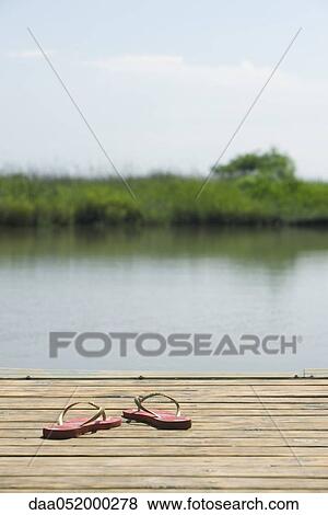 Flip-flops left on dock beside lake View Large Photo Image Stock Photo - Flip-flops left on dock beside lake. Fotosearch
