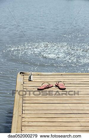 Stock Photo - Flip-flops left on dock beside lake. Fotosearch