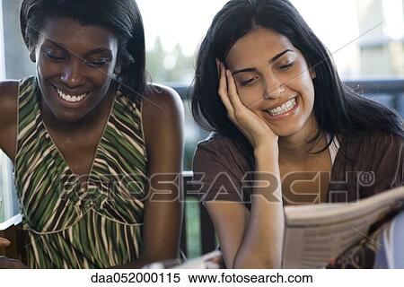 Stock Photography - Friends hanging out together looking at magazines. Fotosearch
