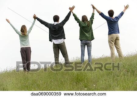 Stock Photo - Friends holding hands, rear view. Fotosearch