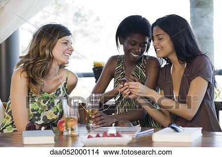 Friends sharing earphones listening to music together View Large Photo Image Picture - Friends sharing earphones listening to music together. Fotosearch