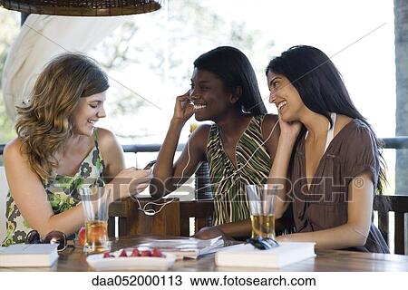Stock Image - Friends sharing earphones listening to music together. Fotosearch