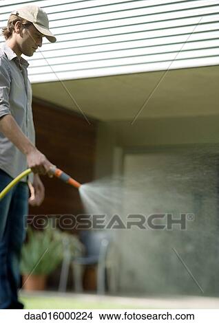 Gardener watering with hose View Large Photo Image Picture - Gardener watering with hose. Fotosearch