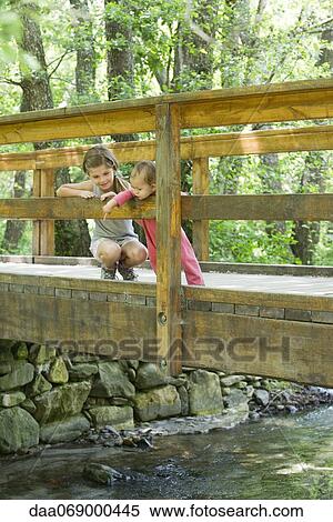Girl and baby sister on bridge, looking down at stream below View Large Photo Image Stock Photography - Girl and baby sister on bridge, looking down at stream below. Fotosearch