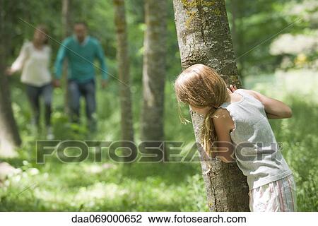 Stock Image - Girl hiding behind tree. Fotosearch