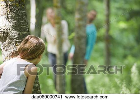 Stock Image - Girl hiding behind tree. Fotosearch