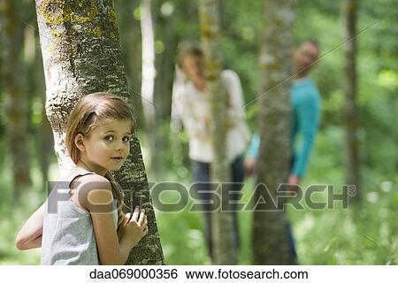 Girl hiding behind tree View Large Photo Image Stock Photograph - Girl hiding behind tree. Fotosearch
