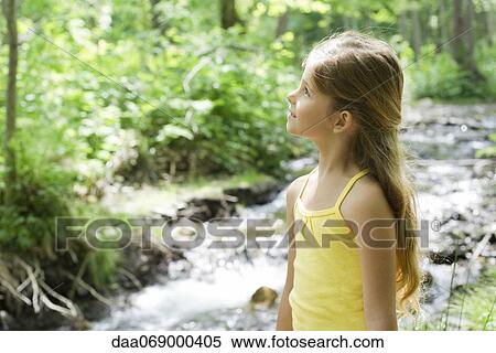 Girl standing beside stream, looking up in awe View Large Photo Image Stock Photography - Girl standing beside stream, looking up in awe. Fotosearch