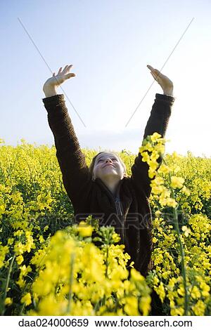 Girl standing in field of canola in bloom, stretching arms over head View Large Photo Image Stock Photo - Girl standing in field of canola in bloom, stretching arms over head. Fotosearch