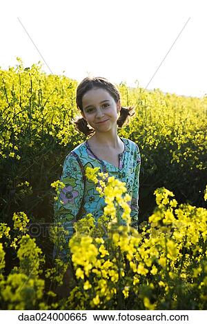 Stock Photography - Girl standing in field of canola in bloom. Fotosearch