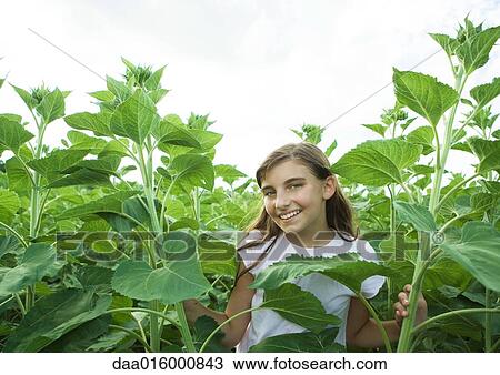 Stock Image - Girl standing in tall plants. Fotosearch