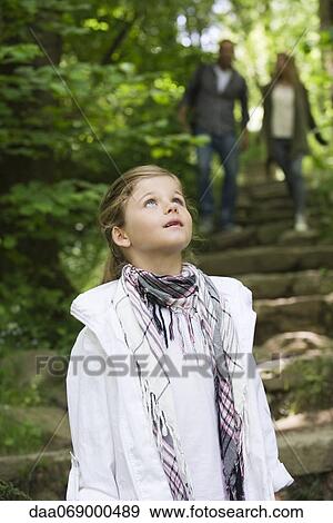 Girl standing in woods, looking up in awe View Large Photo Image Stock Photo - Girl standing in woods, looking up in awe. Fotosearch